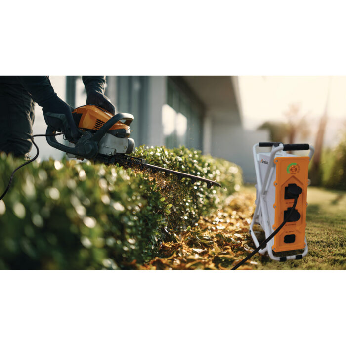 Professional gardener uses an electric hedge trimmer to precisel Professional gardener uses an electric hedge trimmer to precisel